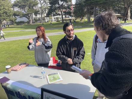 people standing asking questions at table